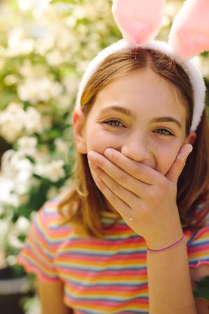 Cheerful girl laughing with her hand on her mouth