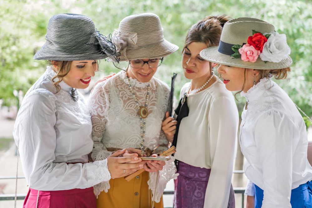Vintage costumed women using smartphone in garden