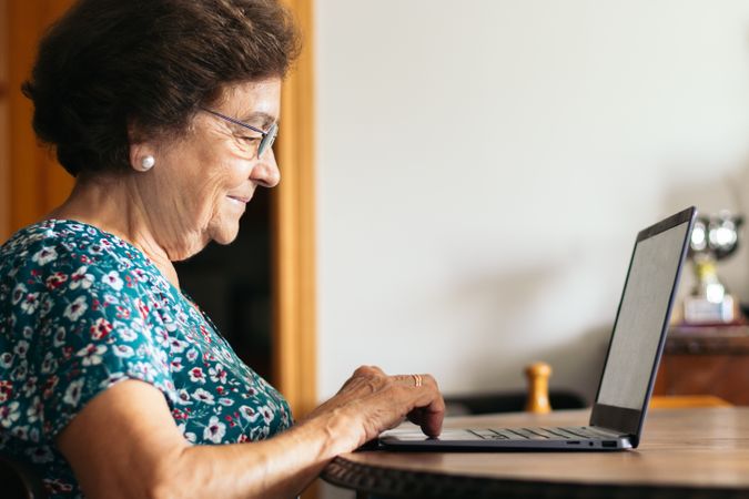 Mature woman with glasses using a laptop at home