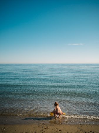 Girl playing with little stones on beach