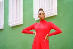 Female in red zipped up shirt standing outside green building
