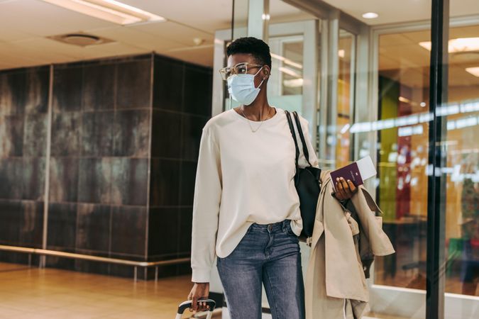 Black woman with face mask walking at airport