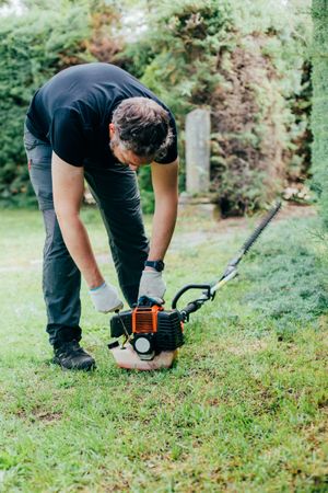 Man switching on a mechanical garden tool