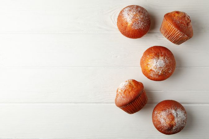 Tasty muffins on wooden background, top view