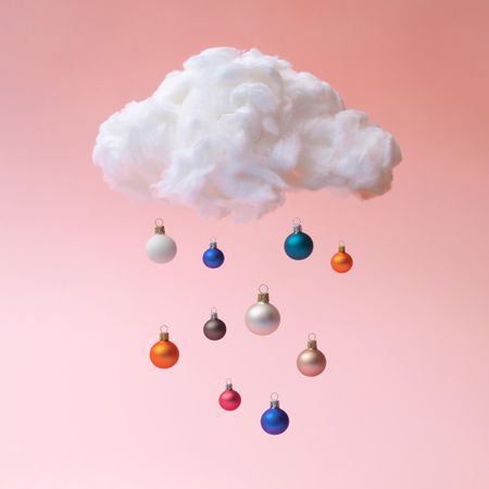 Christmas baubles raining from cloud on pink background