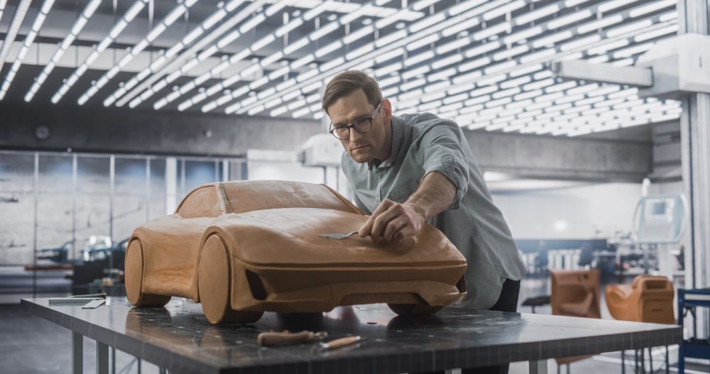 Car Modeler Enjoying Creative Work Process on a Concept Car Made Out of Plasticine Modeling Clay.