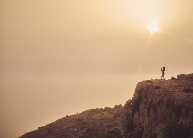 Side view of woman in the distance taking picture of beautiful view