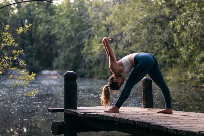 Woman in sportswear doing yoga outdoors near a lake