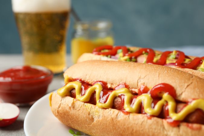 Tasty hot dogs, beer and fries potato on gray table