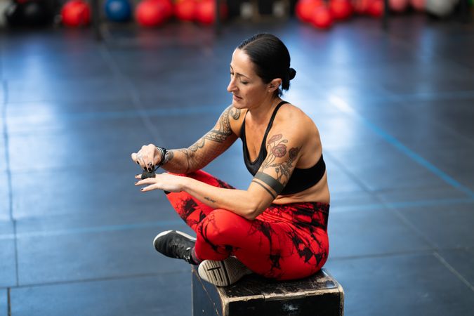Tattooed fit woman wrapping hands in gym
