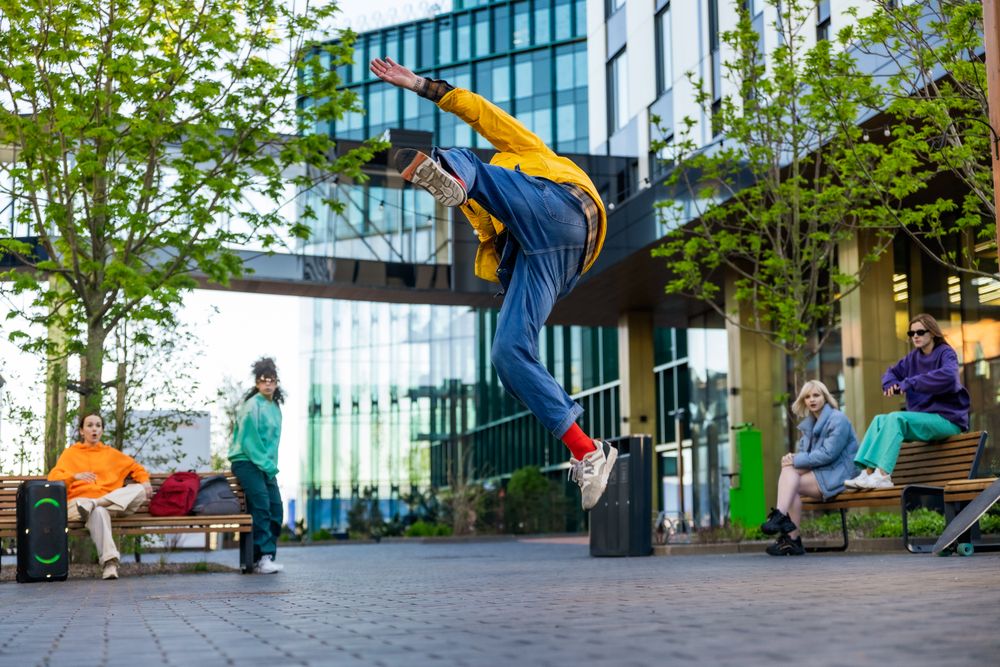 Young Stylish B-boy Breakdancing On City Street Among Modern Buildings In Urban Area.