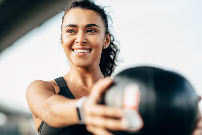 Smiling woman with medicine ball in outstretched arms