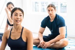 Portrait of Asian woman in sportswear listening to yoga instructor in fitness class