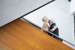 Mature woman kissing her husbands forehead on stairs