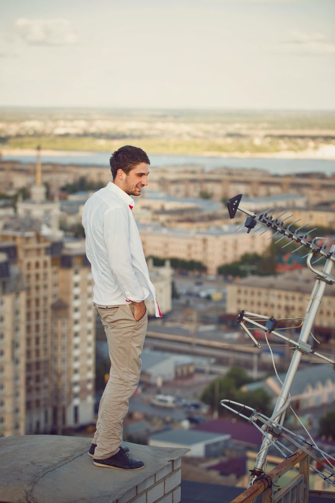 Man stands near satellites on roof enjoying view