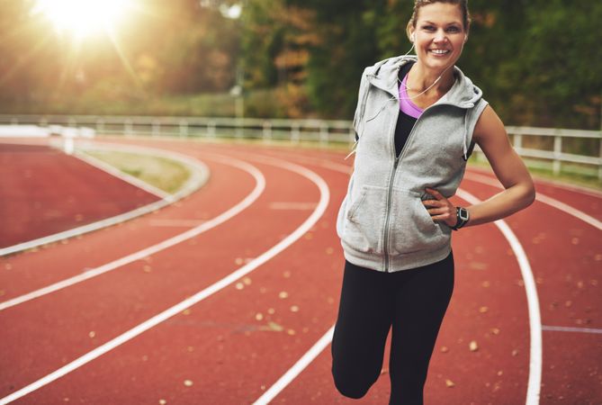 Woman smiling while stretching her quads on athletic track