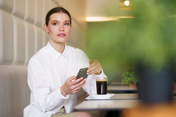 Elegant businesswoman working with mobile sitting in a cafeteria
