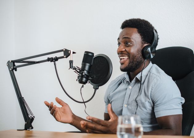 Excited Black man recording podcast in studio