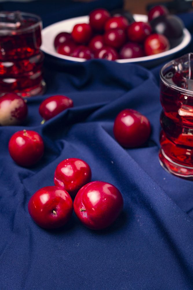 Red beverage near fresh fruits on cloth