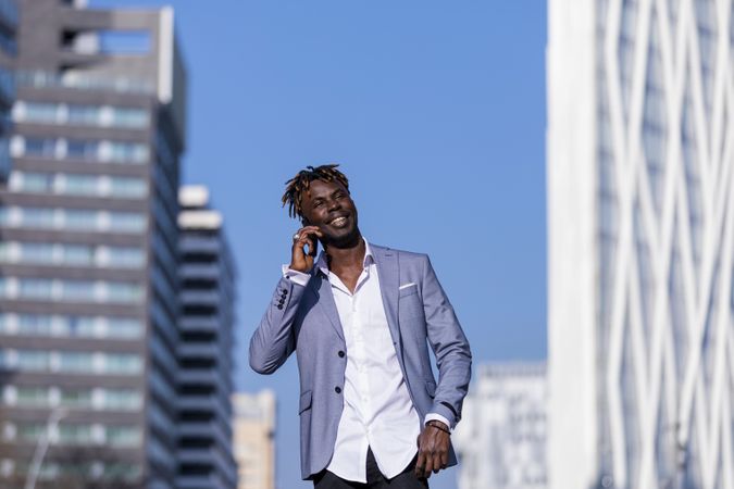 Smiling Black man wearing elegant clothes standing in the street while looking in the distance in sunny day