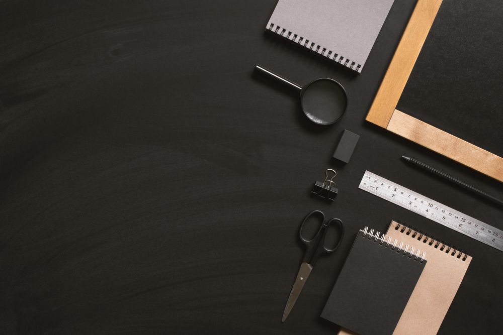 Writing board and stationary on dark background with copy space