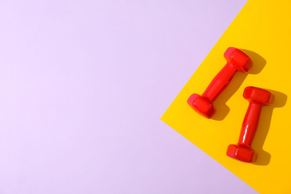 Dumbbells for fitness on two tone background, space for text