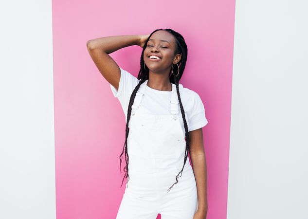 Happy Black woman leaning against pink wall