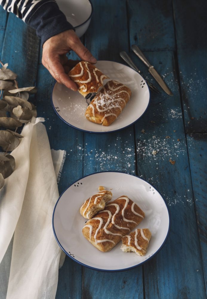 Faceless person taking sweet roll from rustic table