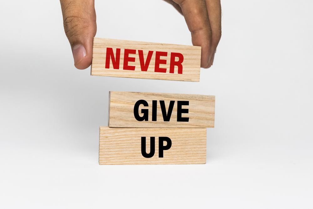 male hand put wooden blocks with never give up words