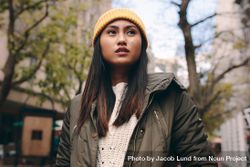 Young woman in yellow knit cap looking to side outdoors 4jEOX5