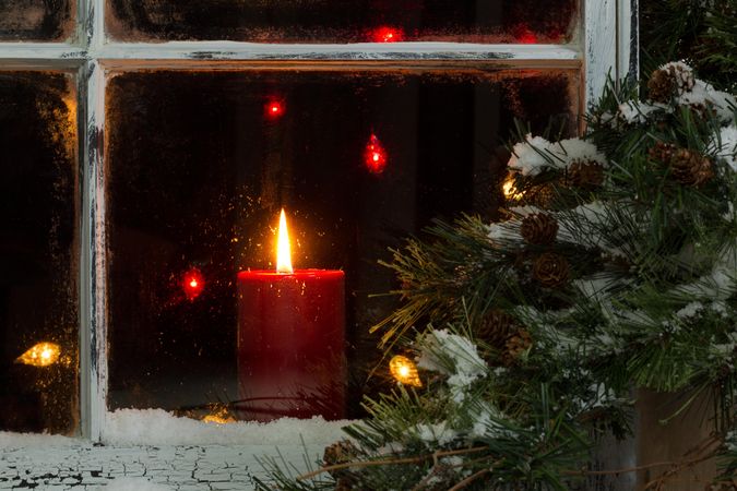 Glowing Christmas red candle in frosted home window
