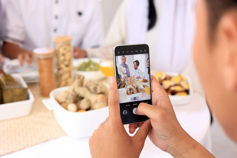 Male Hand Taking Picture of Asian Family and Friend Celebrating Eid Mubarak Festive