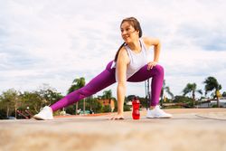 Young sportswoman stretching legs while exercising