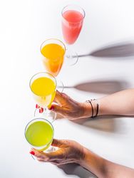 Hand and glasses of bright colorful drinks on table