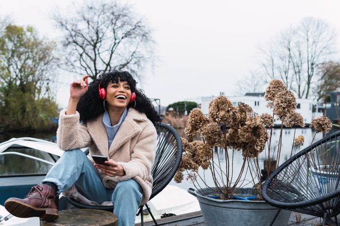 Cheerful Black woman listening to music in park