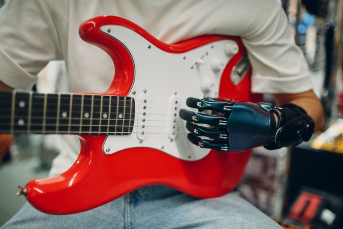 Cropped image of a person playing electric guitar with their prosthetic hand