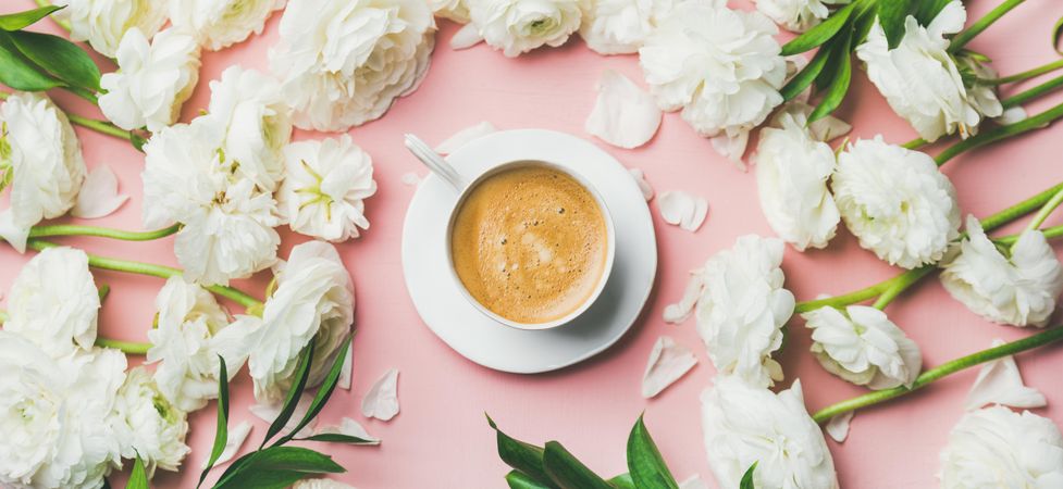 Top view of pretty florals with latte in cup and saucer