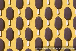 Chocolate popsicle lined up in neat order on a yellow background 5ldZY5