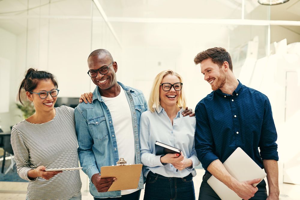 Multi-ethnic group of colleagues smiling together with their notebooks and laptops