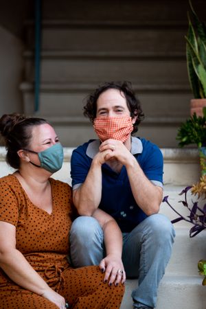 Close up portrait of man and woman wearing masks sitting outside