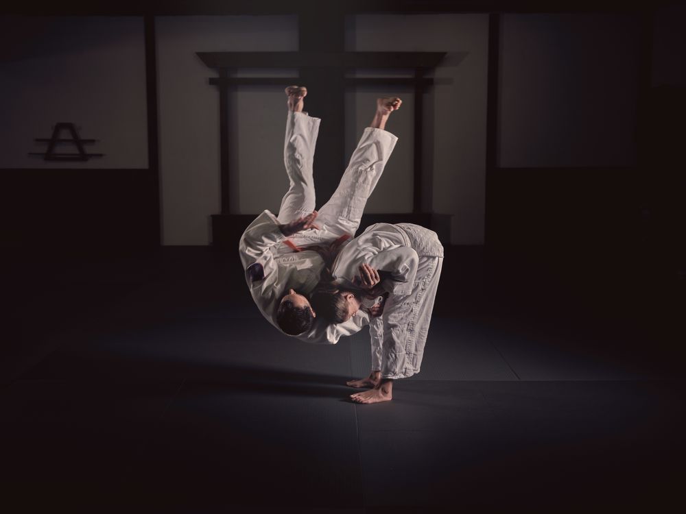 Male and female judo practitioners performing throw exercise in studio