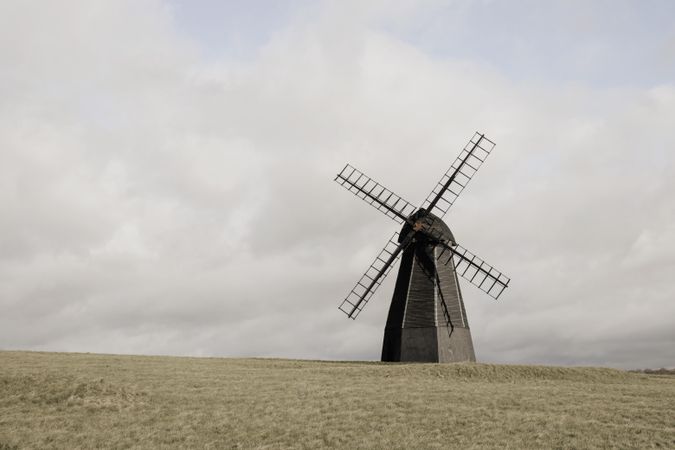 Gray windmill on field under gloomy sky