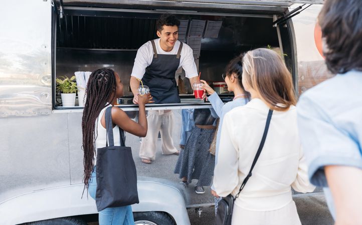 Smiling food vendor selling drinks to customers