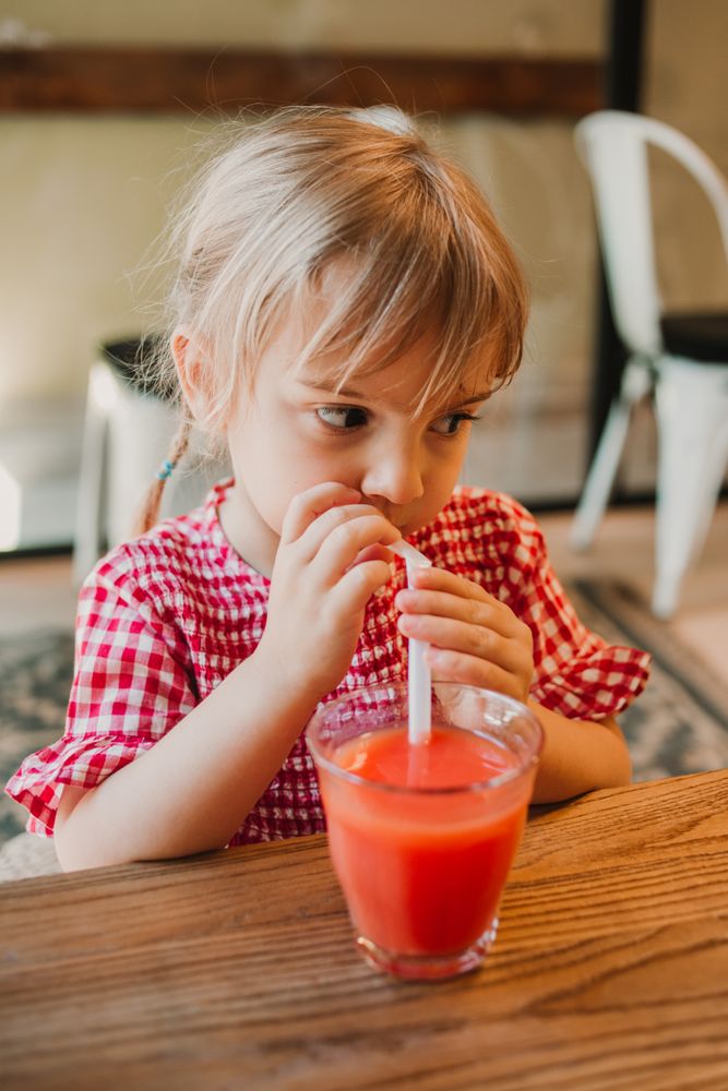 Girl drinking tasty red smoothie through straw