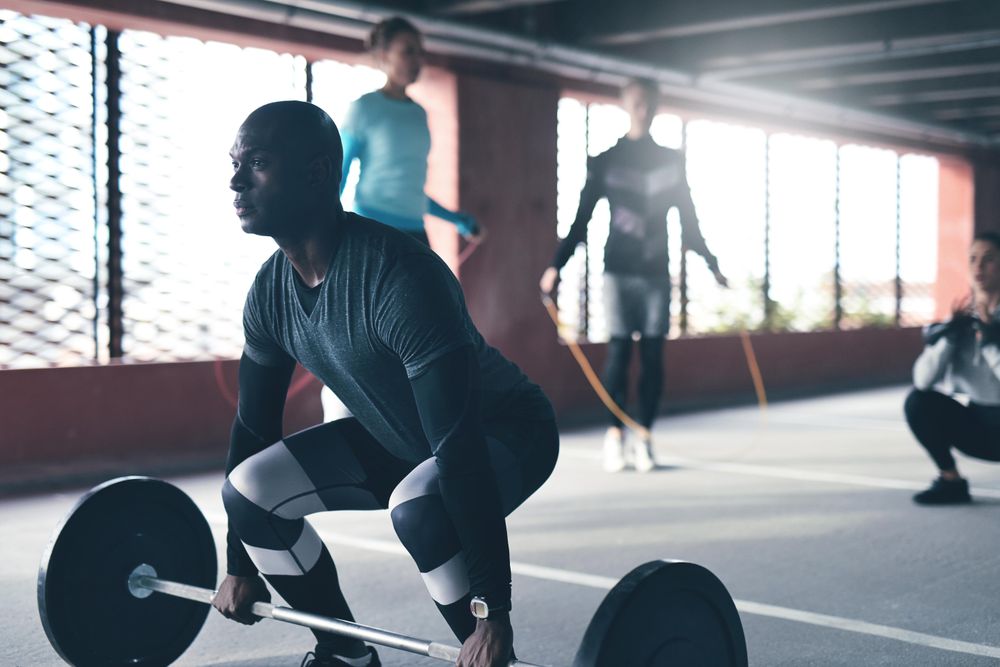 Man reaching down to barbell in gym