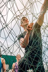 Participant in obstacle course climbing net
