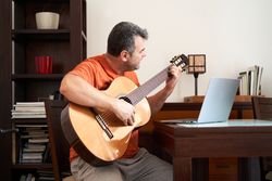 a man with laptop computer in online guitar lessons learning chords