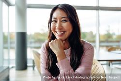 Beautiful Asian woman smiling at camera in large office space bemlGb