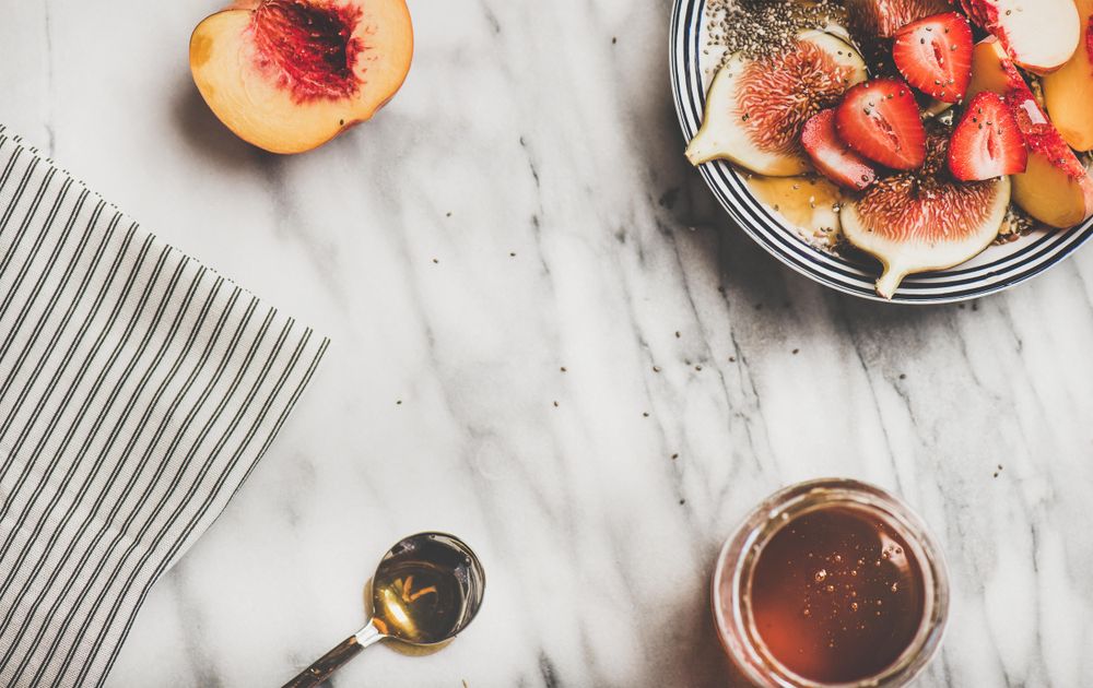 Flat-lay of yogurt bowl with fruit, honey, spoon, copy space