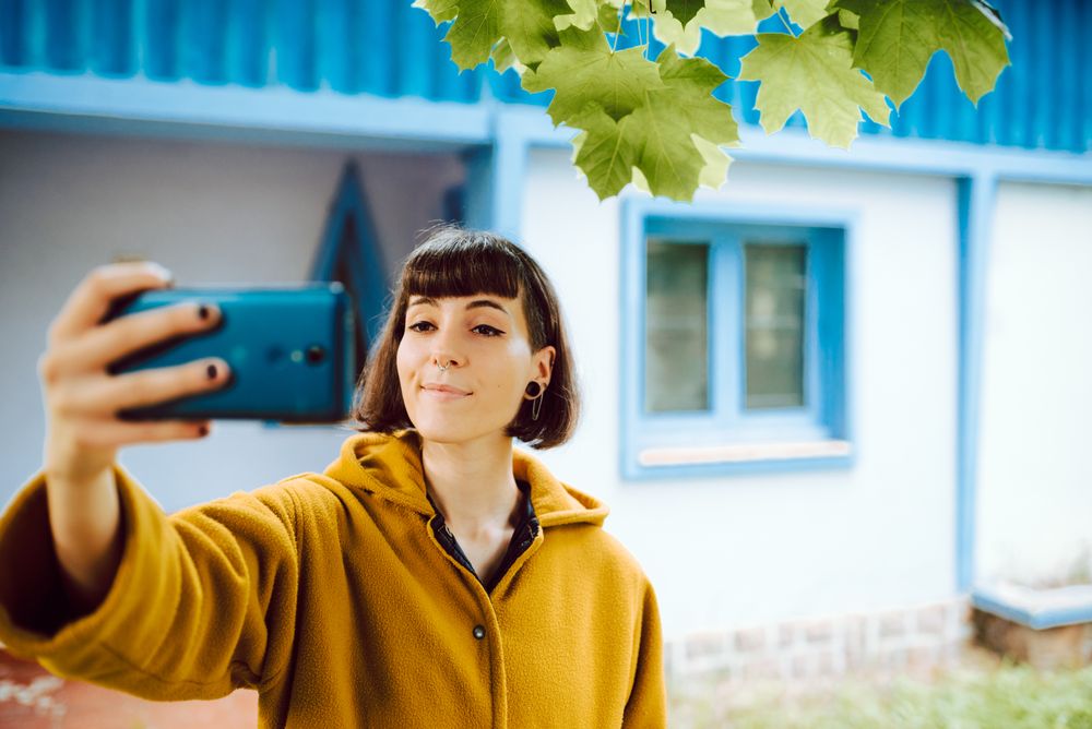 Woman taking selfie against countryside house